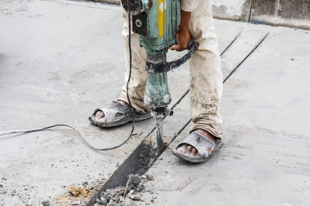 Construction worker using jackhammer drilling concrete surface